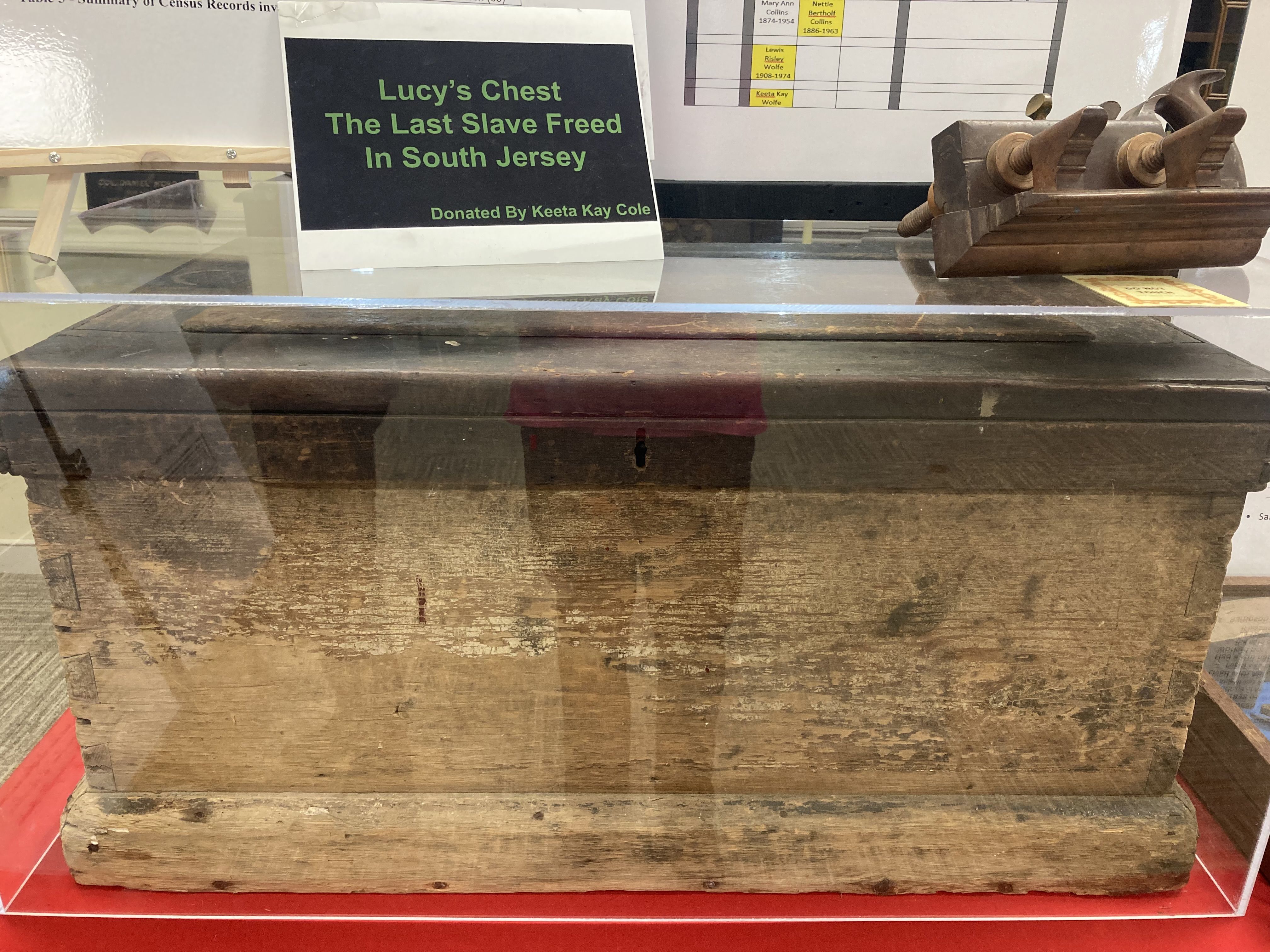 Photograph of old wooden box in a glass case.