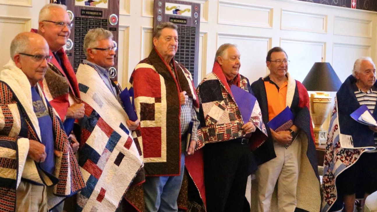 Group of men standing with quilts wrapped around their shoulders. These are veterans who were interviewed for the Veterans History Project. They were honored with the quilts from the Quilts of Valor project.