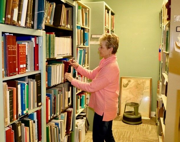 Researcher looking for a book in library bookshelves.