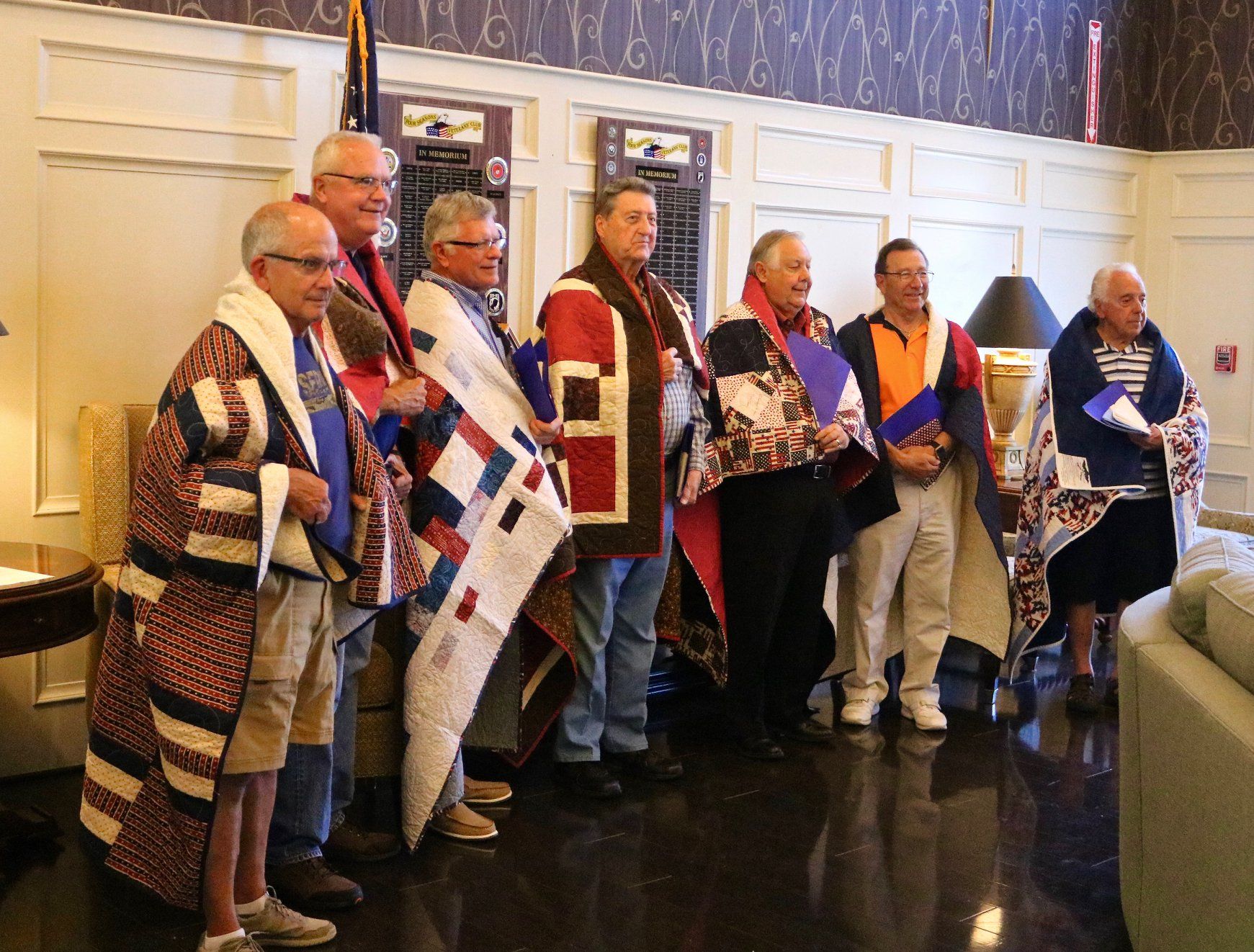 Group of men standing with quilts wrapped around their shoulders. These are veterans who were interviewed for the Veterans History Project. They were honored with the quilts from the Quilts of Valor project.